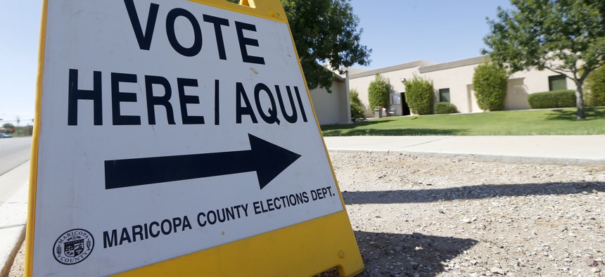 A voting sign directs voters to a precinct on primary election day Tuesday, Aug. 28, 2018, in Phoenix.