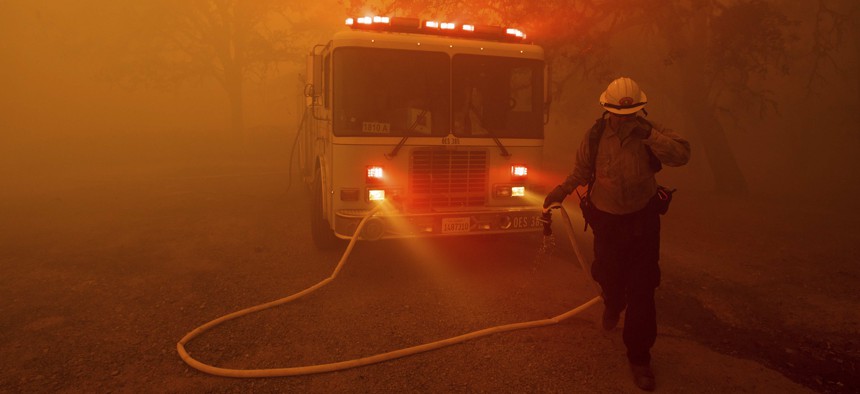 A firefighter rushes to save a home as the River Fire tears through Lakeport, Calif., on Tuesday, July 31, 2018. 