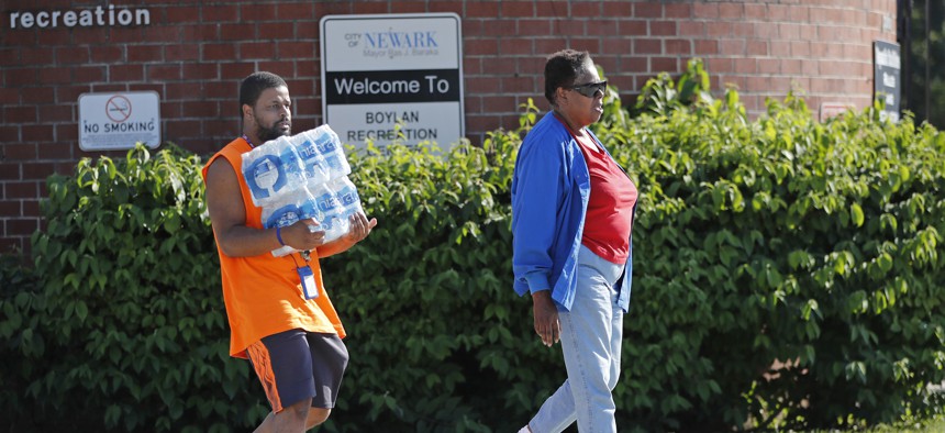 Residents of Newark leave a local recreation center with cases of bottle water distributed by the city.