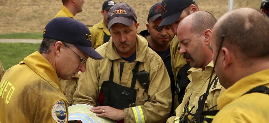 Firefighters combatting a wildfire consult a map of the area. A new technology aims to give fire departments 3-D maps of buildings.