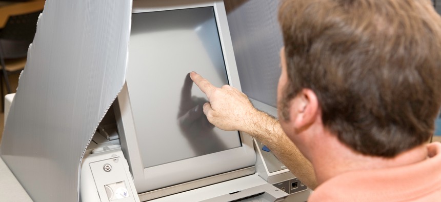 A man votes on a touchscreen voting machine.
