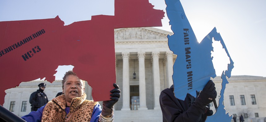 Activists at the Supreme Court opposed to partisan gerrymandering hold up representations of congressional districts from North Carolina, left, and Maryland, right, in March 2019. 