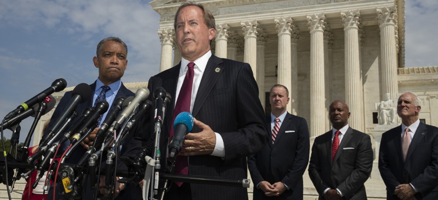 Texas Attorney General Ken Paxton, center, with District of Columbia Attorney General Karl Racine, left, and a bipartisan group of state attorneys general announces an antitrust investigation of big tech companies. an