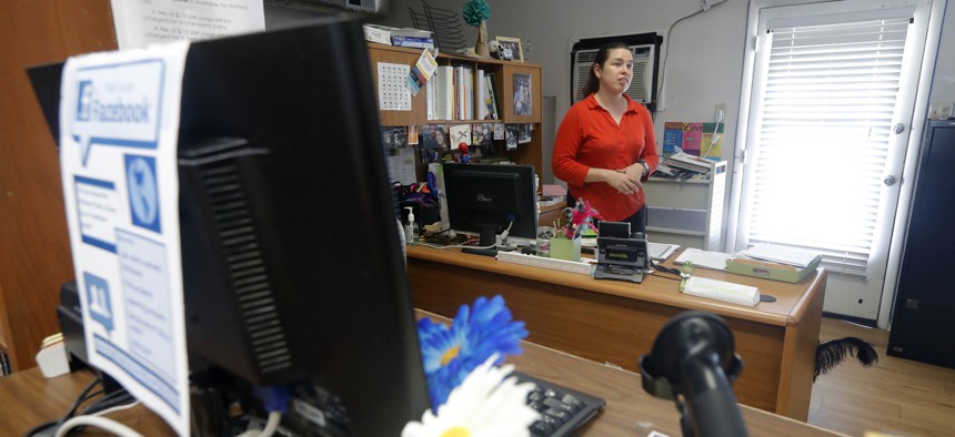 In this Aug. 22, 2019 photo, Library Director Jennifer Ramirez advises a visitor that she is unable to assist him with his request because most of the computers at the public library in Wilmer, Texas, were not working. 