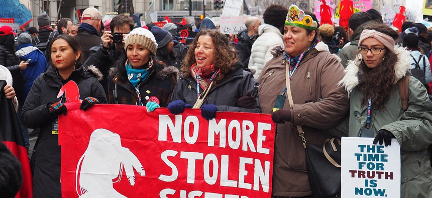 Protestors at the 2019 Women's March in Washington, D.C. hold up a poster highlighting the Missing and Murdered Indigenous Women crisis (MMIW).