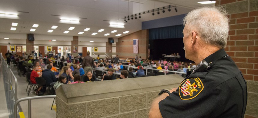 A school police officer stands watch as students eat lunch at a school in Ohio.