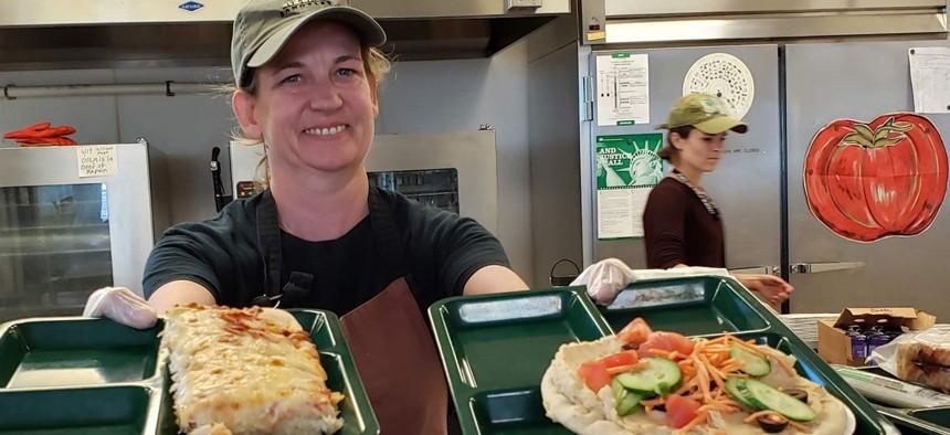 Portland, Maine, school cafeteria worker Alison Mason shows off lunch options at East End Community School, including traditional pizza, left, and vegan pizza with hummus and vegetables. 