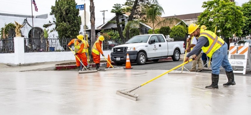Workers apply CoolSeal to a street in Pacoima in June.