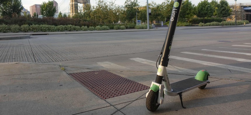 A Lime electric rental scooter parked near a crosswalk awaits a user.