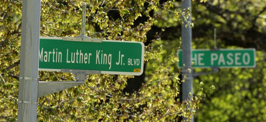In this photo taken April, 20, 2019, a newly changed sign for Dr. Martin Luther King, Jr. Boulevard stands in contrast to a yet-to-be changed sign for The Paseo in Kansas City, Mo.