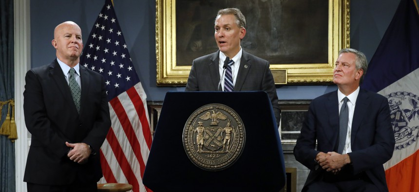 New York City Police Commissioner James O'Neill, left, listens as his successor, Chief of Detectives Dermot Shea, center, speaks at New York City Hall, while New York Mayor Bill de Blasio looks on.