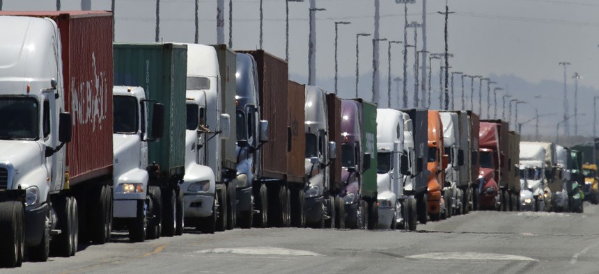 In this July 22, 2019 photo, trucks hauling shipping containers wait to unload at the Port of Oakland in Oakland, Calif.