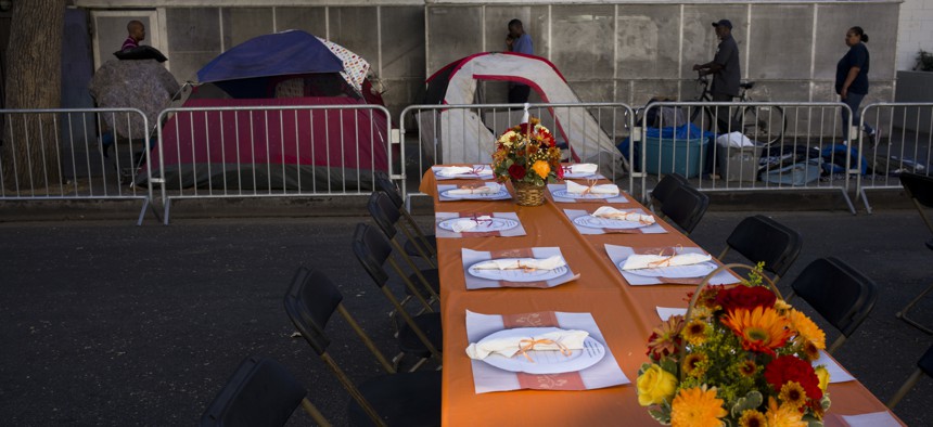 Homeless tents are pitched on a sidewalk in the Skid Row area of downtown Los Angeles Wednesday, Nov. 22, 2017, as tables are set up on the street to serve dinner to homeless people at the Los Angeles Mission's Annual Thanksgiving Dinner Celebration. 