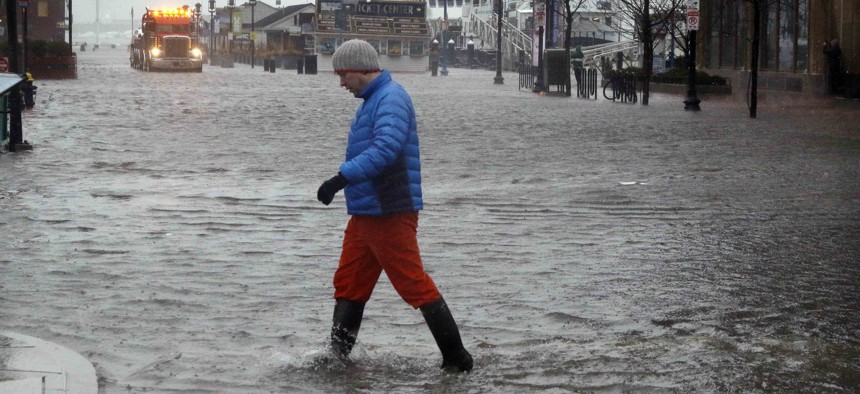 A man walks through water covering State Street in Boston, flooded by water from Boston Harbor at high tide during a major nor'easter that pounded the East Coast, Friday, March 2, 2018.