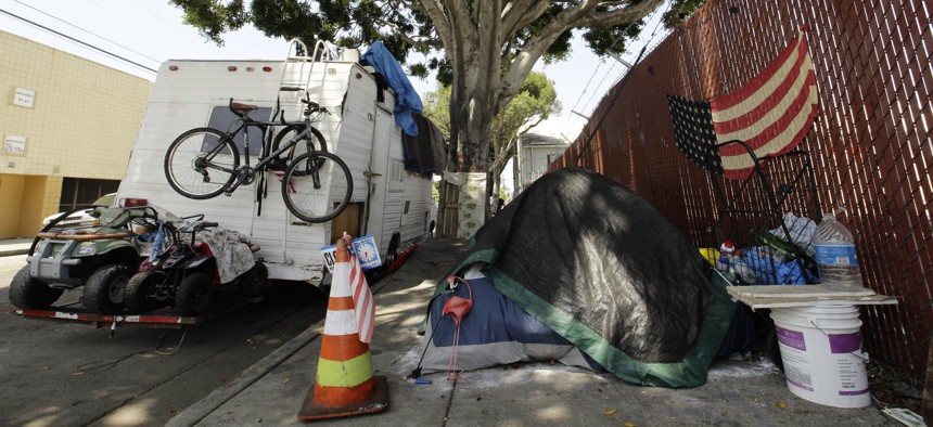 A RV vehicle is parked next to a tent on the streets in an industrial area of Los Angeles, Wednesday, July 31, 2019. 