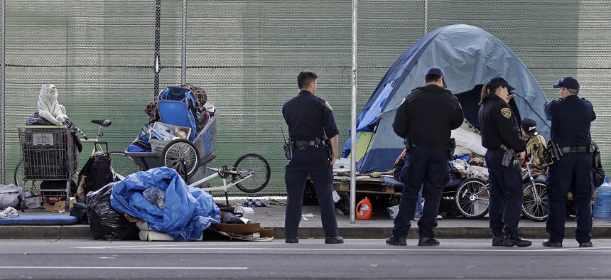 In this March 1, 2016, file photo, San Francisco police officers wait while homeless people collect their belongings in San Francisco. 
