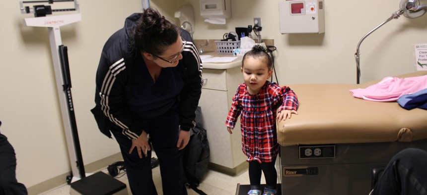 Eliza Oliver helps her daughter, Taelyn, step down from the exam table after her wellness check at Community Health Center. 