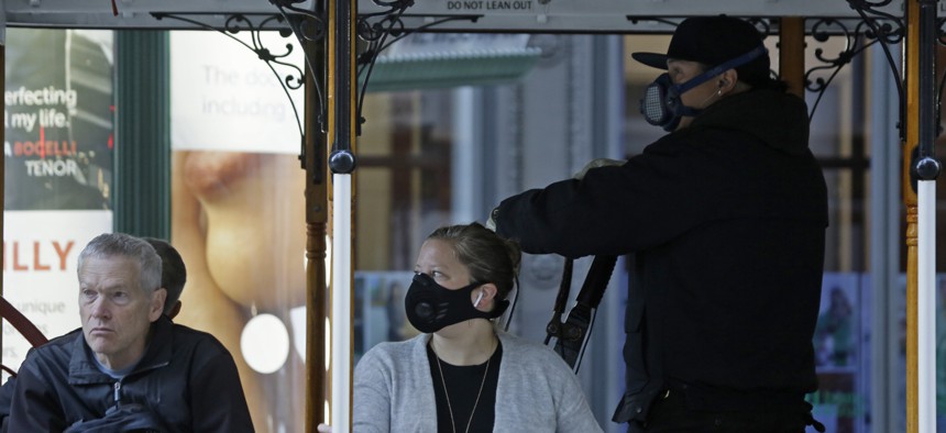 A San Francisco street cable car operator and passenger wear breathing masks to protect against smoke from wildfires on Oct. 28, 2019. 