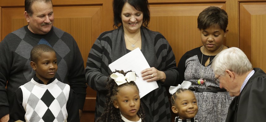 Judge James Cissell talks with twin sisters Lauriana and Laylah after they were adopted by Greg and Robin Smith, along with their brother Laurence and sister Liasia. A record number of children in foster care are being adopted.