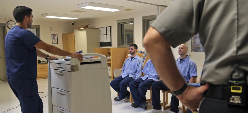 In this July 23, 2018, photo, inmates at Franklin County Jail in Massachusetts are watched by nurse Brian Toia, left, and a corrections officer after they received their daily doses of buprenorphine, a drug which controls heroin and opioid cravings.