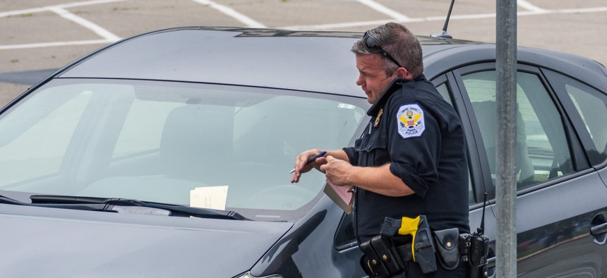 Parking enforcement writes a ticket in San Francisco. The city recently reevaluated its parking ticket fines and fees.
