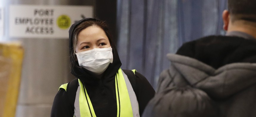 An airport agent wears a protective mask as she waits to assist international travelers at SeaTac International Airport on Monday. 