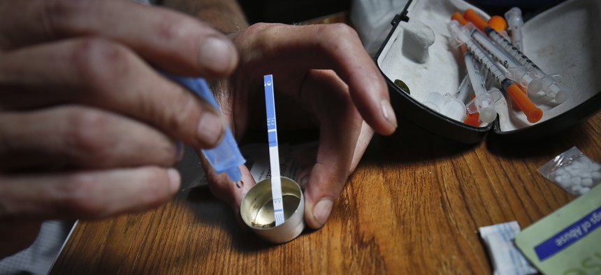 A drug user prepares heroin, placing a fentanyl test strip into the mixing container to check for contamination.