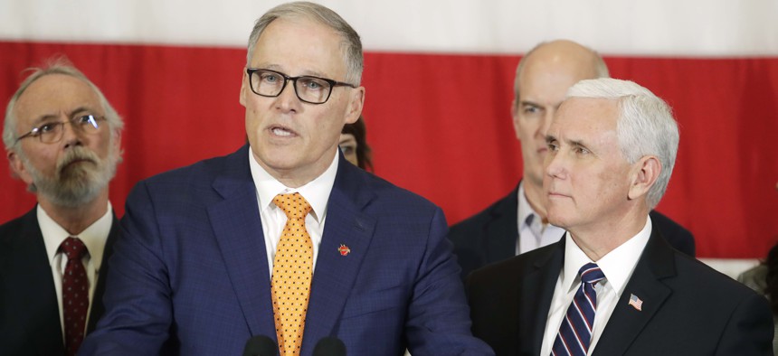 Vice President Mike Pence, right, looks on as Gov. Jay Inslee speaks during a news conference, Thursday, March 5, 2020, at Camp Murray in Washington state. Pence was in Washington to discuss the state's efforts to fight the COVID-19 coronavirus.