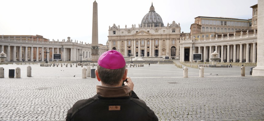 A prelate takes a photo of an empty St. Peter's Square at the Vatican on March 10, 2020. Italy entered its first day under a nationwide lockdown after a government decree extended movement restrictions to the whole country to respond to the coronavirus.