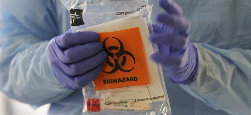 A nurse at a drive up COVID-19 coronavirus testing station, set up by the University of Washington Medical Center, holds a bag containing a swab used to take a sample from the nose of a person in their car, Friday, March 13, 2020, in Seattle.