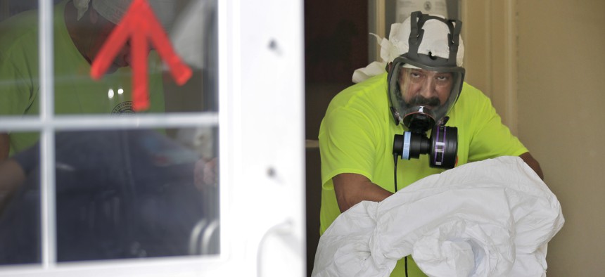 A member of a cleaning crew removes his protective gear after sanitizing a bank in New Rochelle, New York.