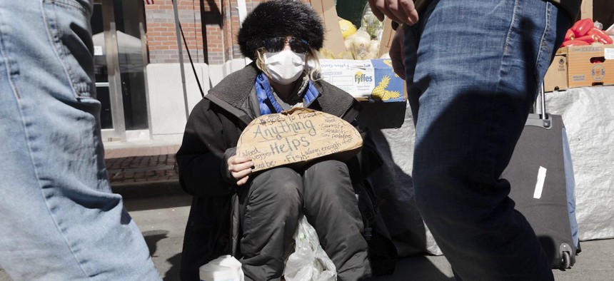 A homeless woman going by the name of Miss Bee seeks donations at an outdoor produce market in Boston, Saturday, March, 14, 2020. 