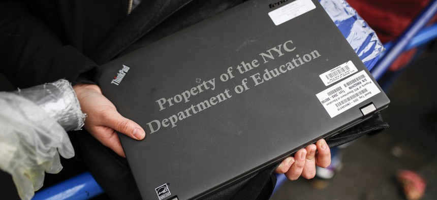 A student receives her school laptop for home study at the Lower East Side Preparatory School in New York. 