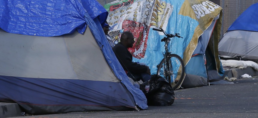 A homeless man sits in a tent in Sacramento, Calif., Friday, March 20, 2020. Gov. Gavin Newsom has authorized $150 million in emergency funding to protect homeless people in the state from the spread of COVID-19. 