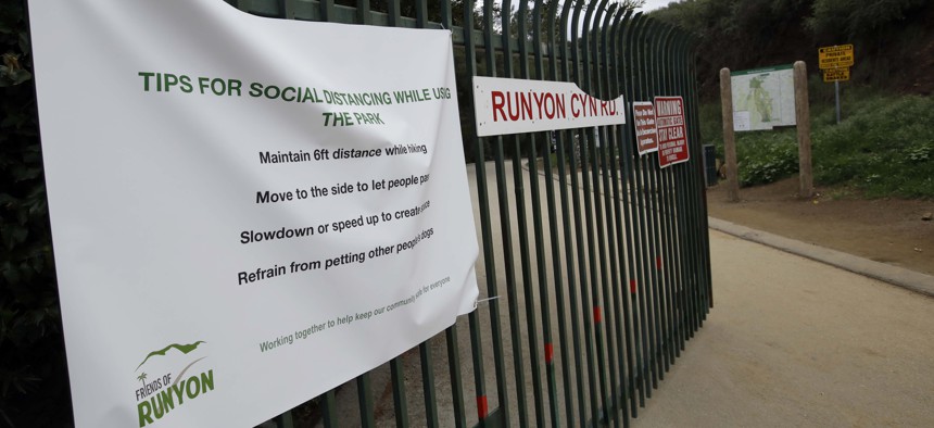 A signs issues instructions for social distancing as Runyon Canyon park announces a closure Wednesday, March 25, 2020, in Los Angeles. 