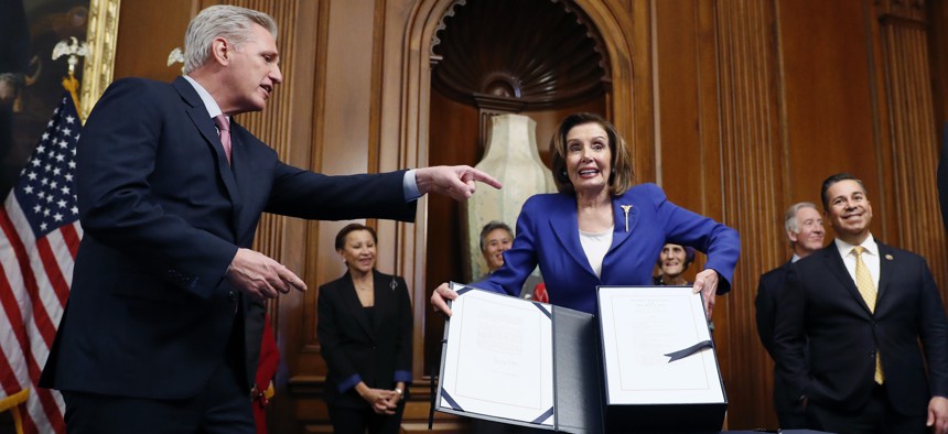 House Speaker Nancy Pelosi, accompanied by House Minority Leader Kevin McCarthy, and other legislators, participate in a bill enrollment ceremony for the CARES Act, after it passed in the House, on Capitol Hill, Friday, March 27, 2020 in Washington.