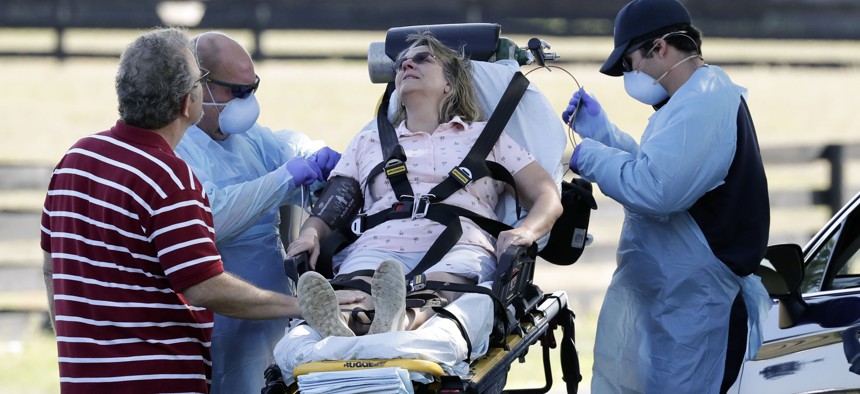 Medical personnel treat a woman shortly after she arrived at a coronavirus mobile testing site Monday, March 23, 2020, in The Villages, Fla. She was later transported to a medical facility by ambulance. 