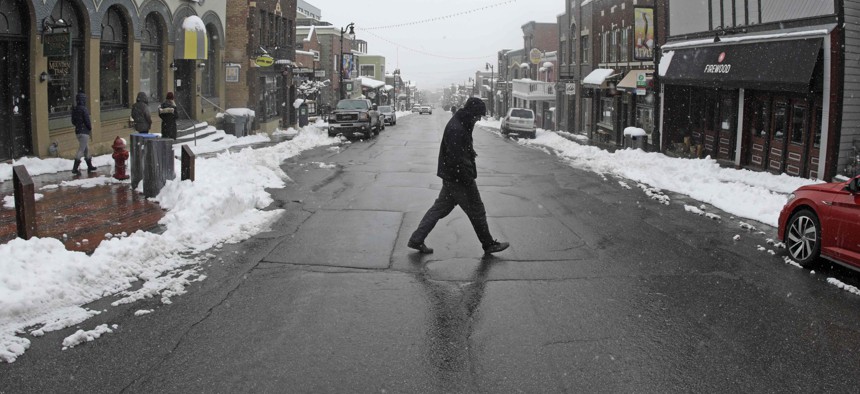 A man walks across Main Street Thursday, March 26, 2020, in Park City, Utah. After seeing a surge of coronavirus cases, Summit County issued an order for all residents to not leave their homes unless necessary.