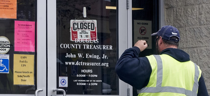 A man is confronted with a closed sign at the Douglas County Treasurer's office in Omaha, Neb. on March 18, 2020. In-person services were suspended due to the coronavirus outbreak. 