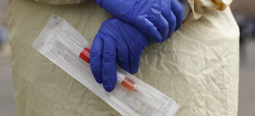 A nurse holds a swabs and test tube kit to test people for COVID-19, the disease that is caused by the new coronavirus.
