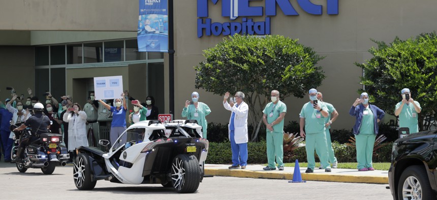 Medical workers cheer as first responders drive by in a procession to honor hospital staff at Mercy Hospital during the new coronavirus pandemic, Friday, April 10, 2020, in Miami.