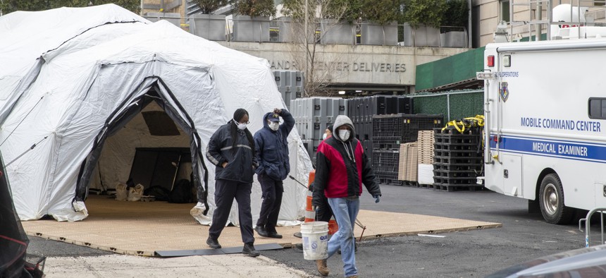 Medical Examiner personnel and construction workers are seen at the site of a makeshift morgue being built in New York City on March 25, 2020. 