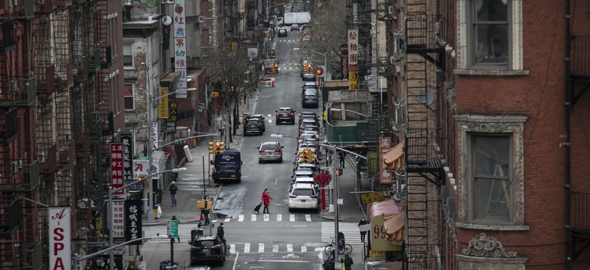 A woman pulls her grocery cart as she crosses the streets in Chinatown, on Thursday, March 19, 2020, in New York.
