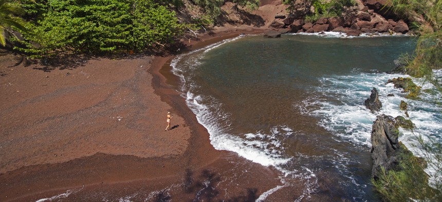  In this Sept. 24, 2014 file photo, a woman walks on the red sand beach at Kaihalulu Bay in Hana, Hawaii. 