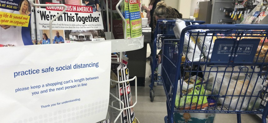 A sign alerts shoppers to practice social distancing, due to the coronavirus, while in the checkout line at a grocery store, Saturday, March 28, 2020 in Troy, Mich.