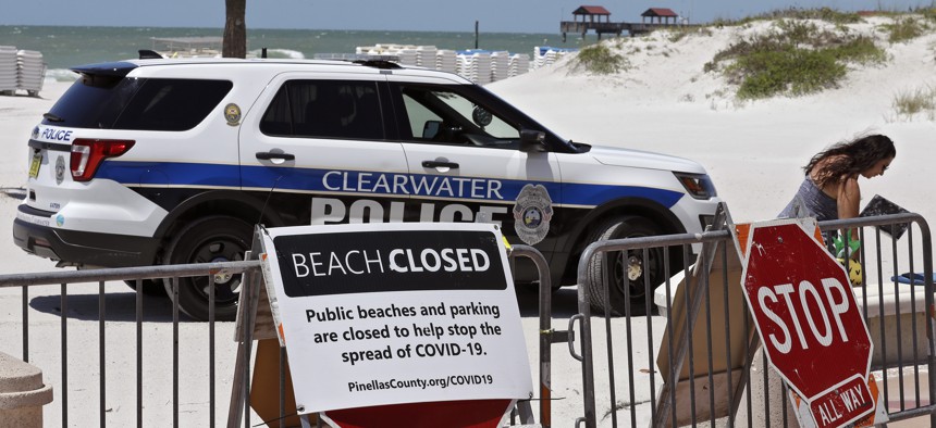 A Clearwater police officer asks a woman who was sitting on Clearwater Beach to leave Thursday, April 30, 2020, in Clearwater Beach, Fla. The beach is temporarily closed to avoid the spread of the coronavirus. 