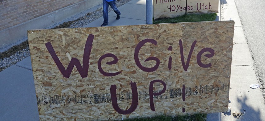 A man walks past a "we give up" sign outside Euro Treasures Antiques Friday, May 8, 2020, in Salt Lake City. The U.S. unemployment rate hit 14.7% in April, the highest rate since the Great Depression.