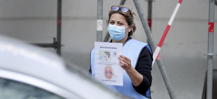 A staff member of the local health authority holds an information poster on how to use a new coronavirus test kit at a new drive-in testing center in Berlin, Germany on April 24, 2020. 