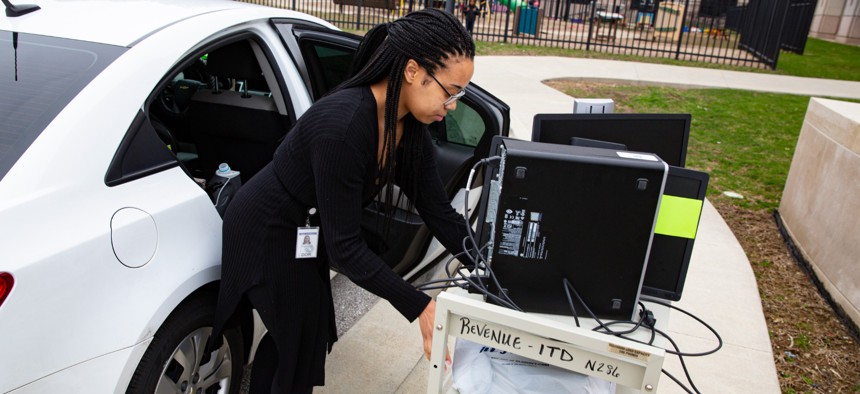 An employee at the Indiana Department of Revenue moves her computer equipment from her office at the State office complex in Indianapolis on March 24, 2020, to allow her to work from home.