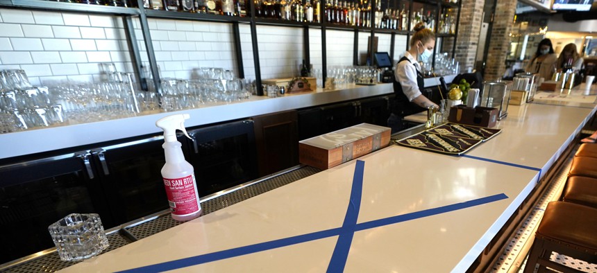 A bottle of sanitizer sits on the bar as tape marks an area to keep clear for social distancing at a Houston restaurant on April 24, 2020.
